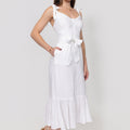 Woman wearing a white Buttoned Linen Midi Dress With Tie Straps and Ruffled Hem with a plain background