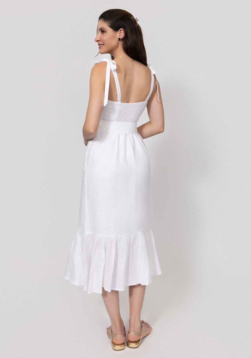 Woman wearing a white Buttoned Linen Midi Dress With Tie Straps and Ruffled Hem on a light gray background