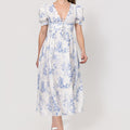 Woman wearing a floral Linen Button-Front Midi Dress with Puff Sleeves & Tie Detail on a white background