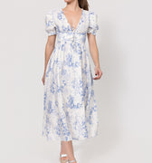 Woman wearing a floral Linen Button-Front Midi Dress with Puff Sleeves & Tie Detail on a white background