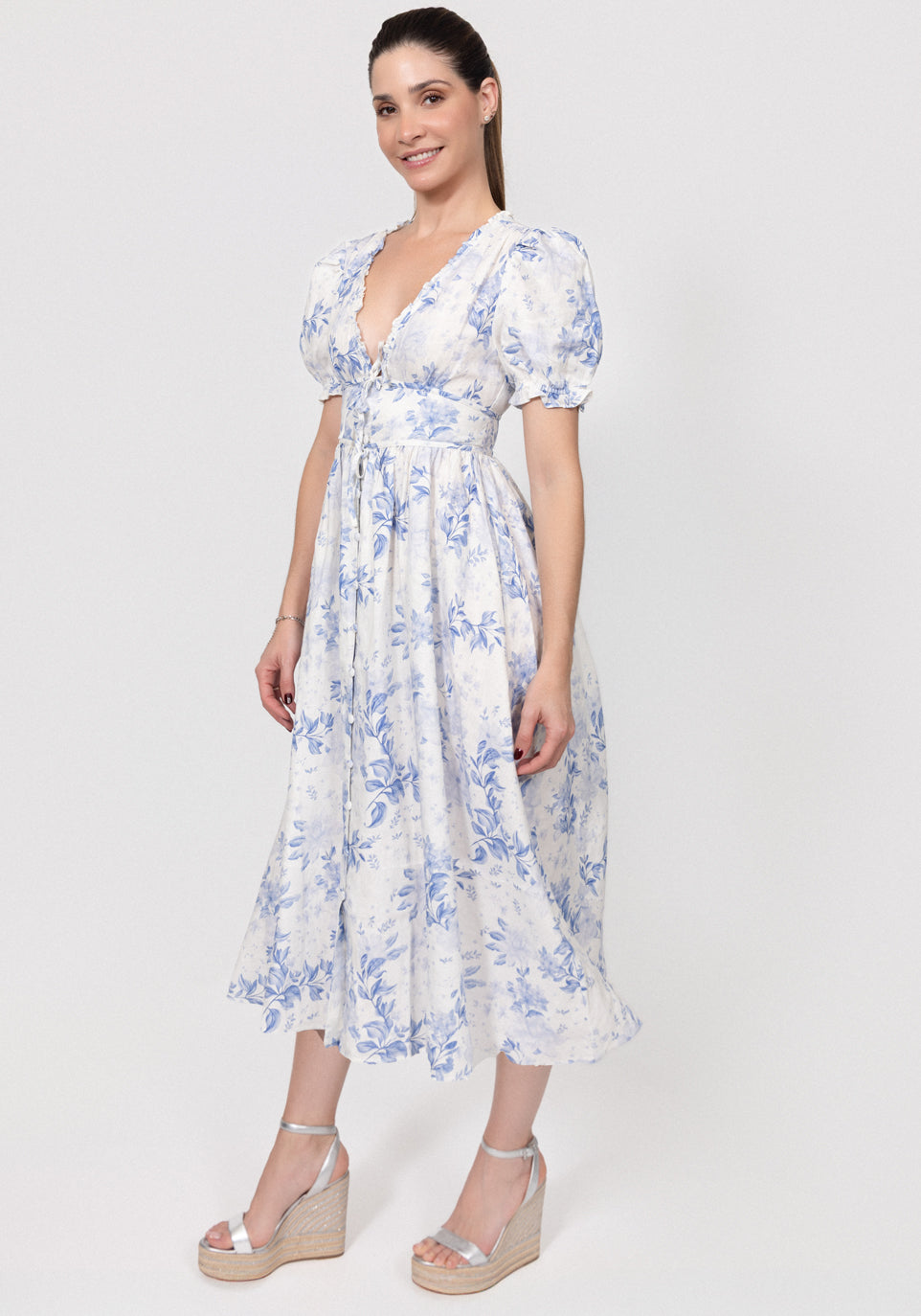 Woman wearing a floral Linen Button-Front Midi Dress with Puff Sleeves & Tie Detail on a white background