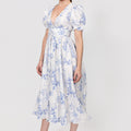 Woman wearing a floral Linen Button-Front Midi Dress with Puff Sleeves & Tie Detail on a white background