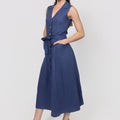 Woman wearing a navy blue linen button dress with a white background