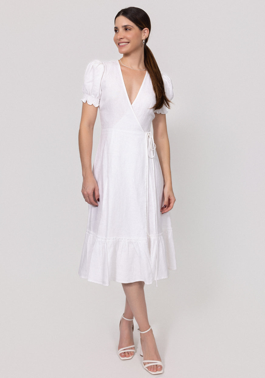 Woman wearing a white Linen Wrap Dress with Puff Sleeves and Ruffle Hems on a light gray background
