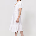 Woman wearing a white Linen Wrap Dress with Puff Sleeves and Ruffle Hem on a plain background