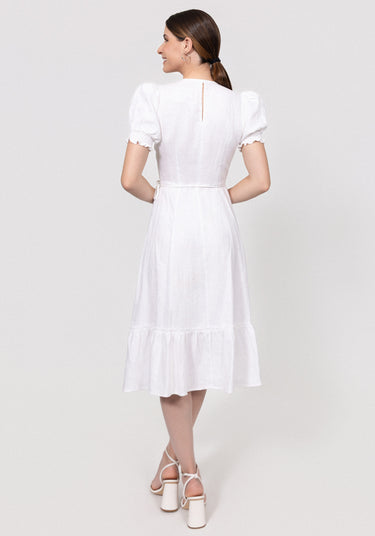 Woman wearing a white dress with ruffled sleeves and hem on a light gray background