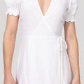 White dress with short sleeves and a deep neckline on a plain background
