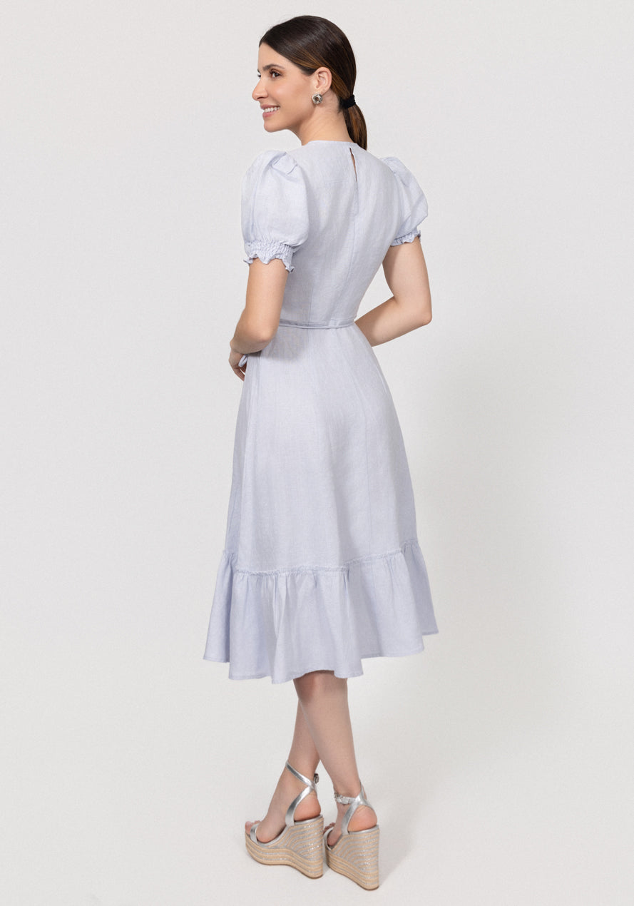 Woman wearing a light blue Linen Wrap Dress with Puff Sleeves and Ruffle Hem on a white background