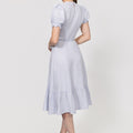 Woman wearing a light blue Linen Wrap Dress with Puff Sleeves and Ruffle Hem on a white background