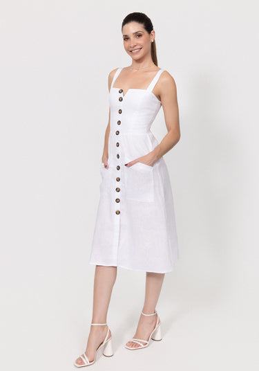 Woman wearing a white linen dress with buttons and pockets on a white background