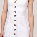 White dress with brown buttons on a plain background