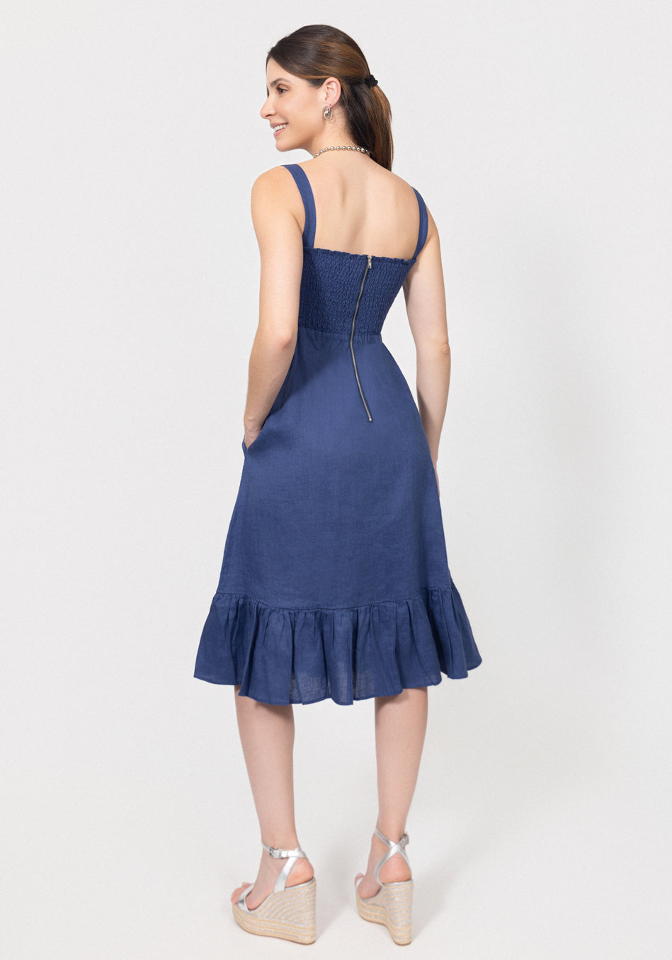 Woman wearing a blue dress with a ruffled hem on a white background